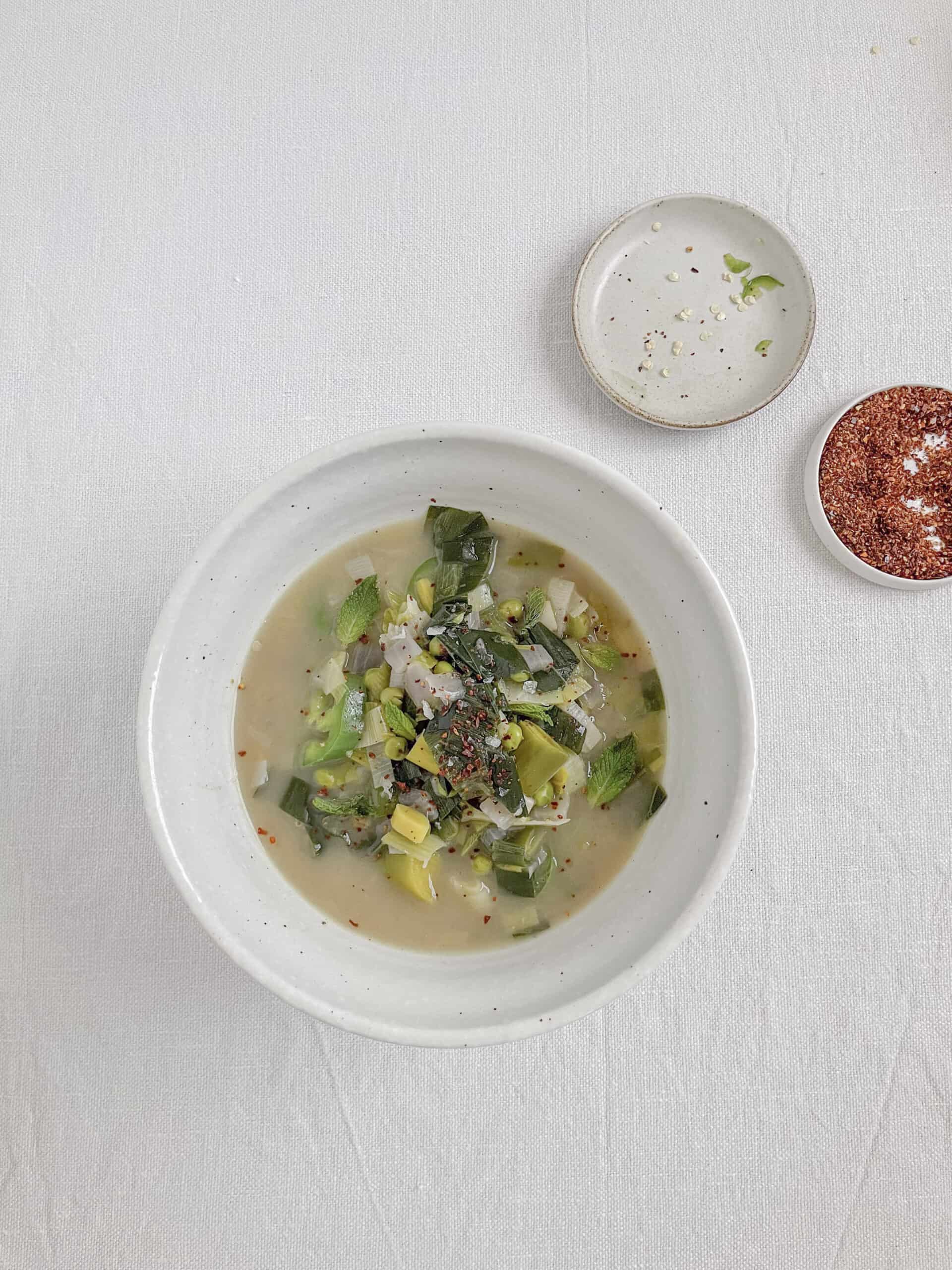 leek soup in a white bowl on the table with a white table cloth.