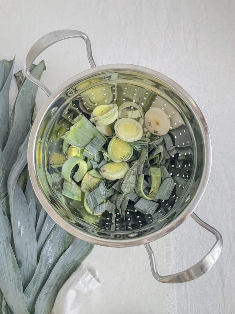 sliced leeks in a colander ready to be cleaned.