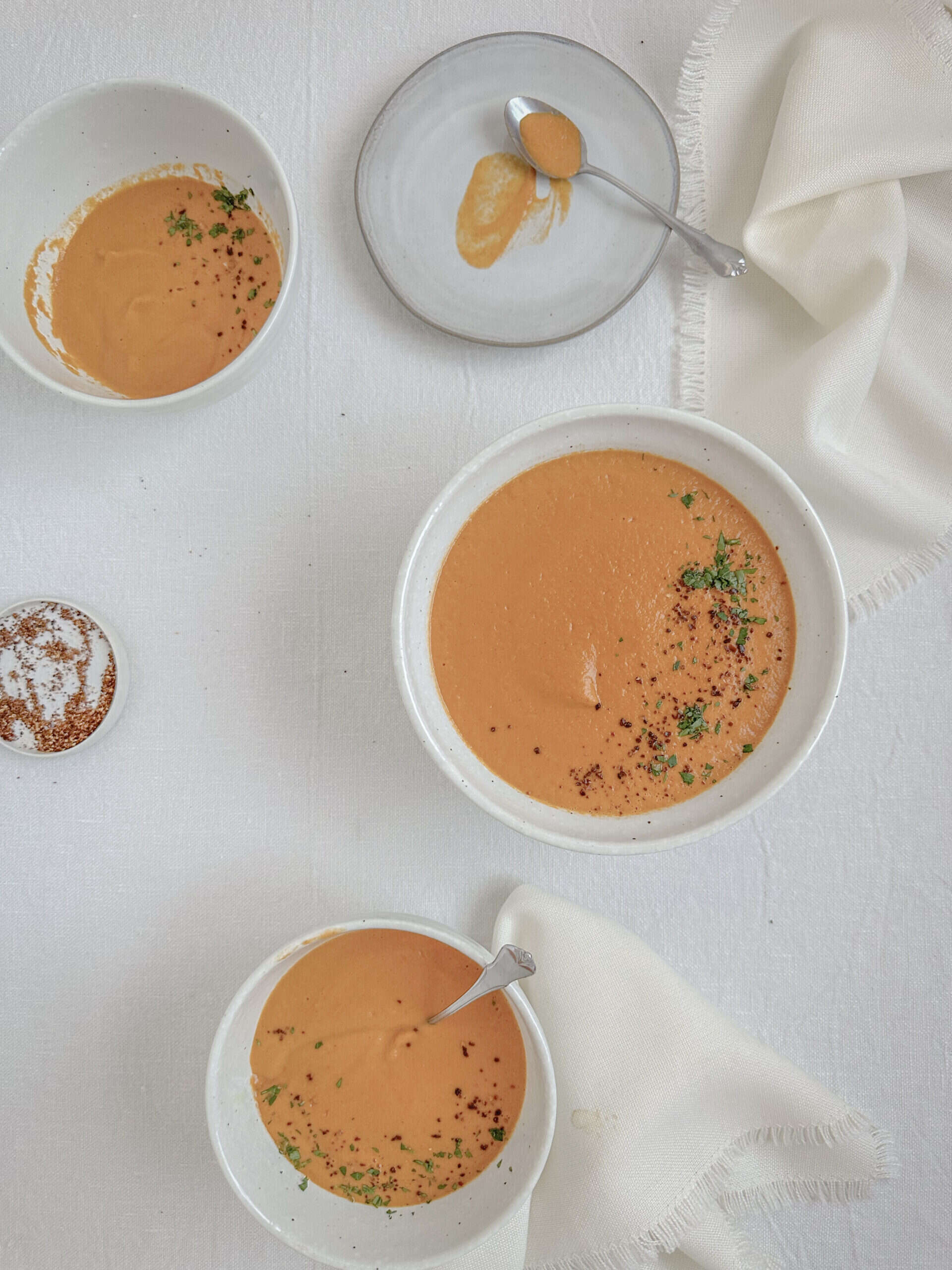 tomato soup in soup bowls on the table with a white tablecloth
